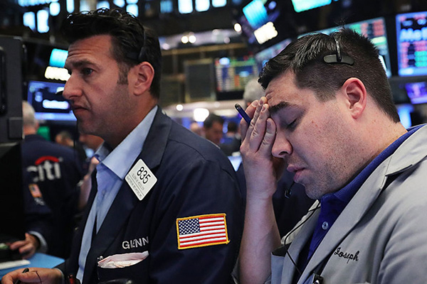 two stock traders appear distressed on the trading floor